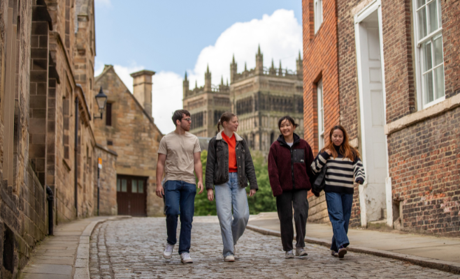 Four students walk in a line down from the cathedral