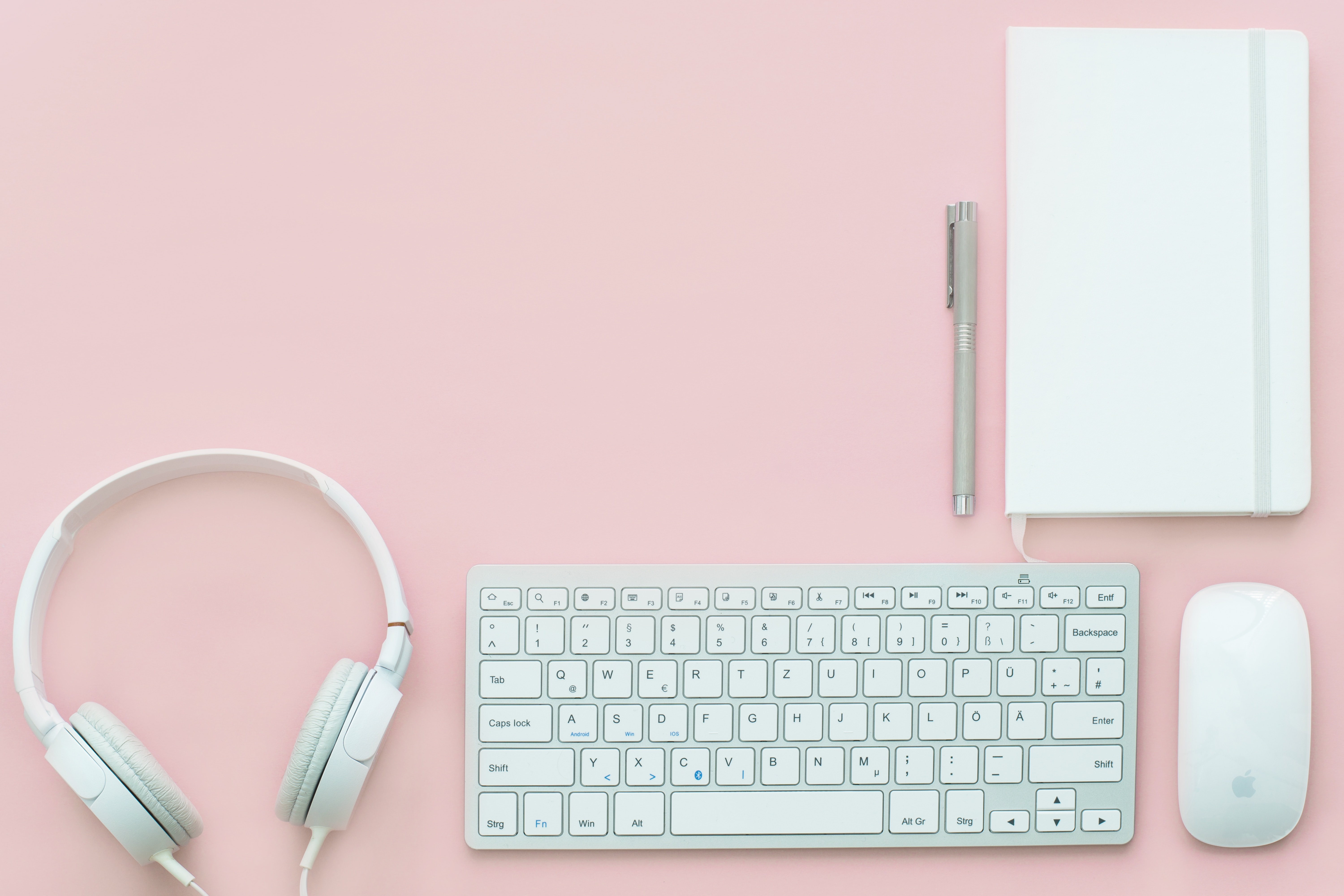 white keyboard and headphones against pink background