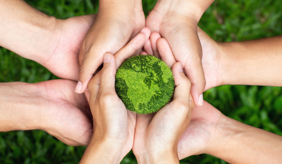 A group of hands holding a globe made of grass