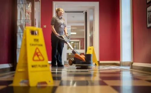 Housekeeper cleaning floor with machine