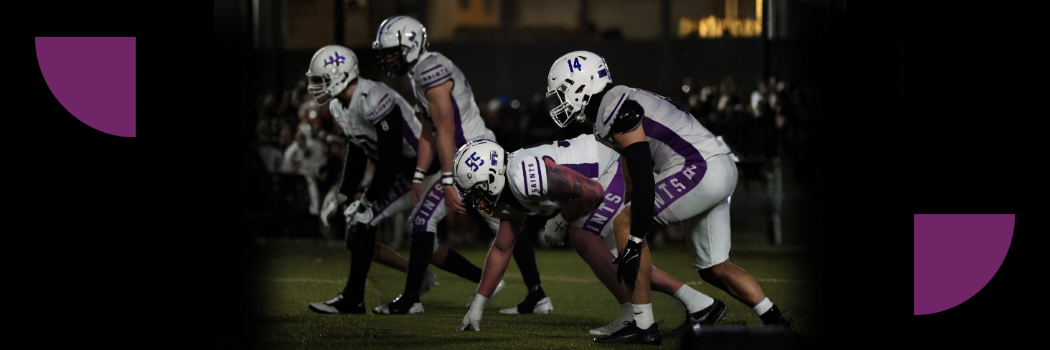A line up of American Football players wearing white and purple strips.