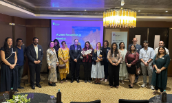 Gathered alumni in a line in front of a presentation screen