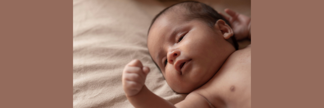 Newborn baby asleep on a bed.