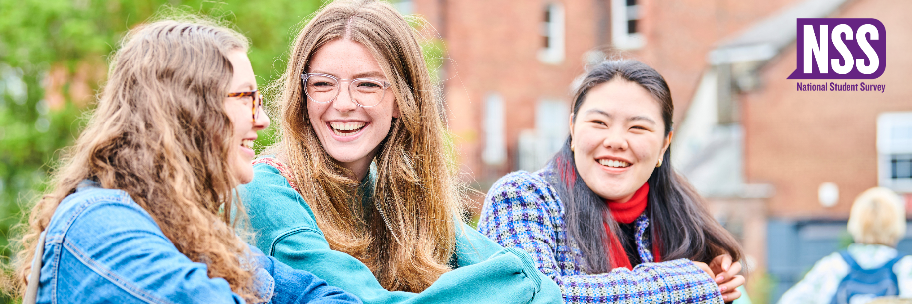 Three students leaning on a bridge having a conversation and smiling