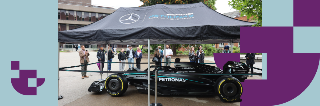 A black formula 1 racing car underneath a black Mercedes-AMG PETRONAS canopy.