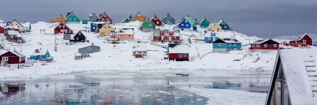 A small town of brightly coloured wooden houses stands in a frozen landscape