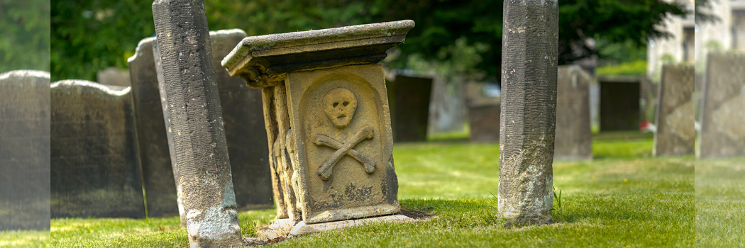 An old gravestone with a skull and crossbones engraved in it.