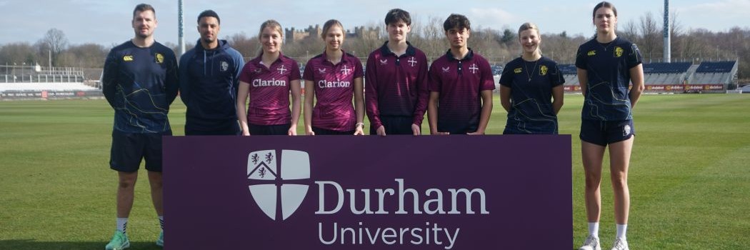 Members of the University Cricket Club and Durham Cricket Club standing with a Durham University purple banner.