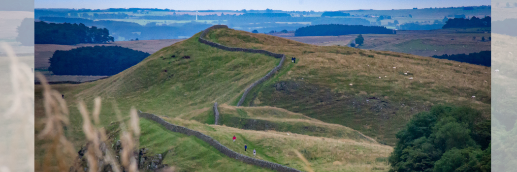 An ancient stone wall running through a hilly landscape.