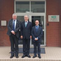 Three people standing outside a brick building