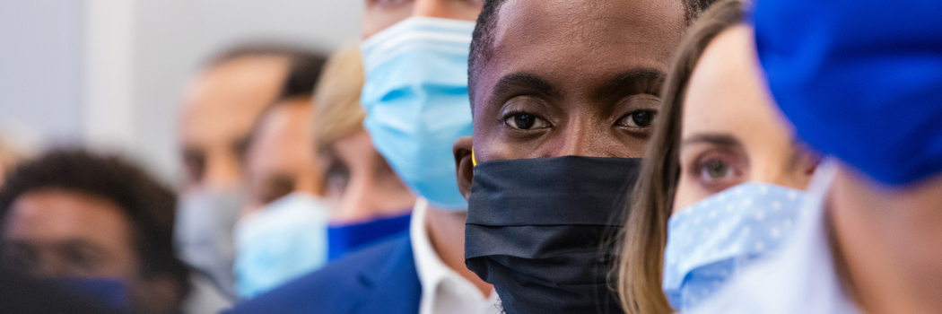 A line of white people wearing medical facemasks with a black person in the centre