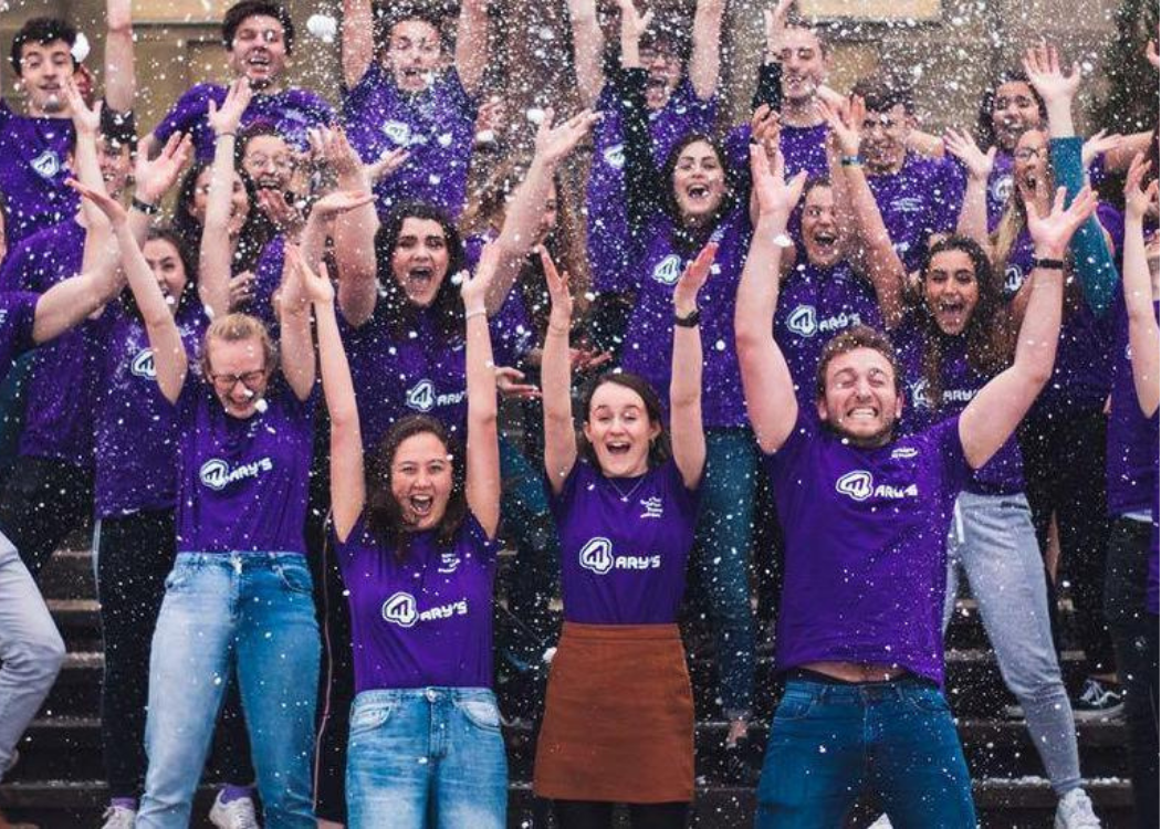 A large group of students with their hands in the air cheering