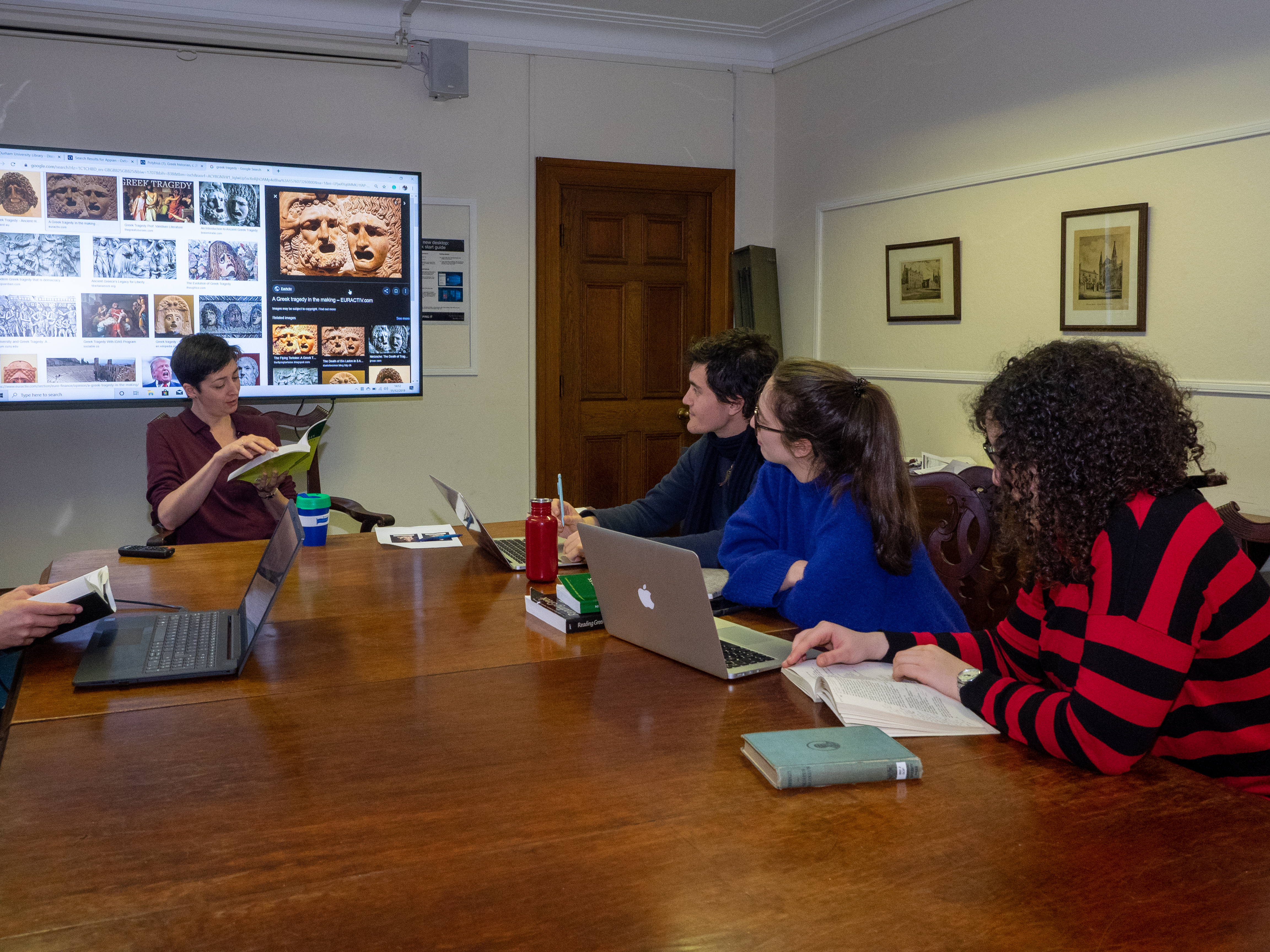 Lecturer teaching to students around table.