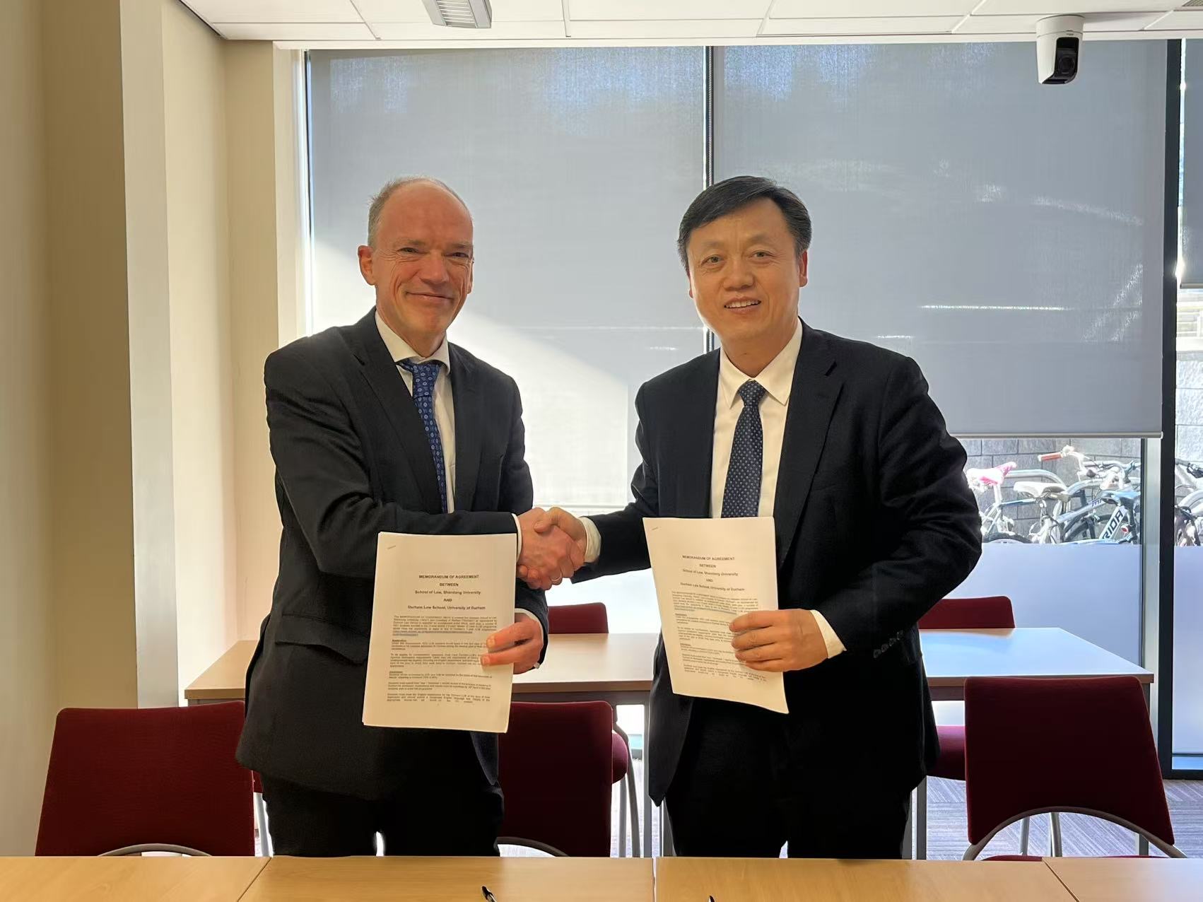 Dean Professor Volker and Dead Professor Zhou Changjun shaking hands and smiling