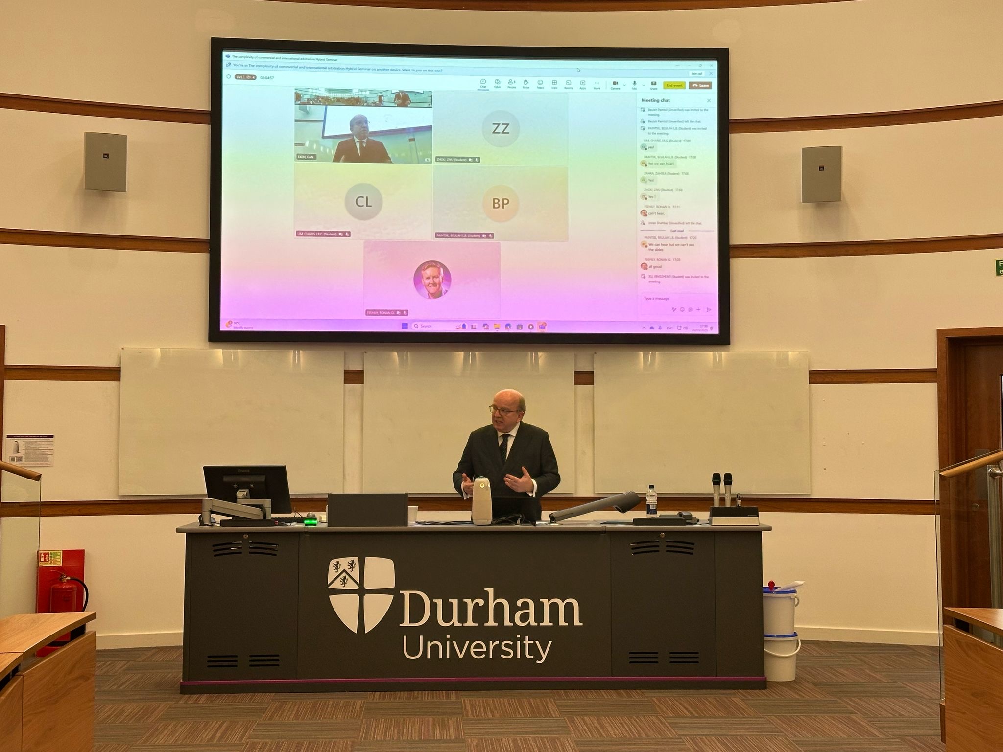 A professor in front of a screen, talking to the audience