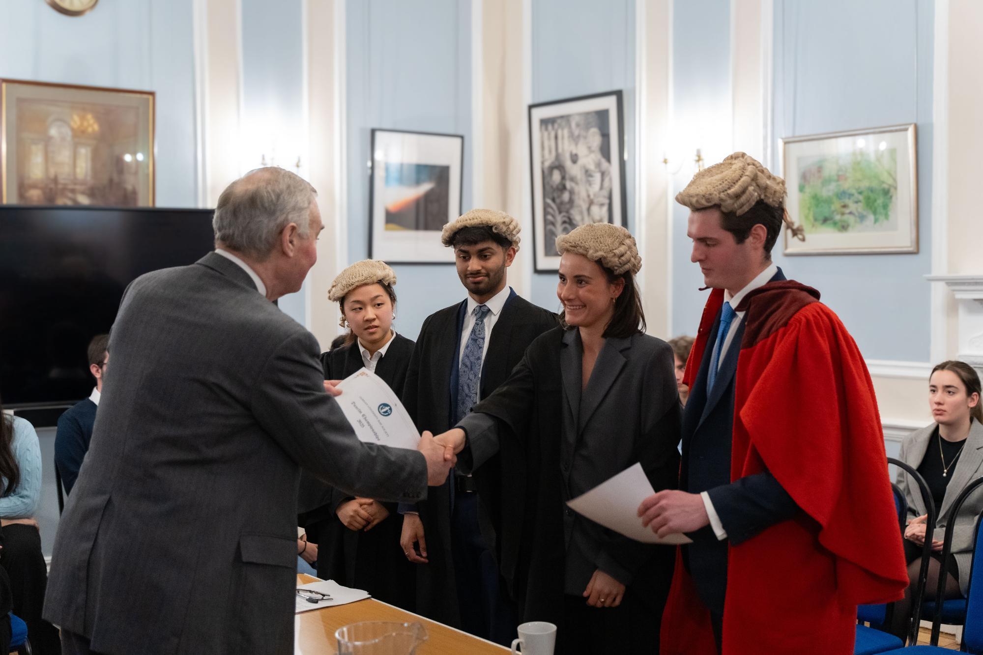 Lord Hughes shaking the hand of Celina Barton, with Duncan Roesser, Shray Modi, and Soryoung Han