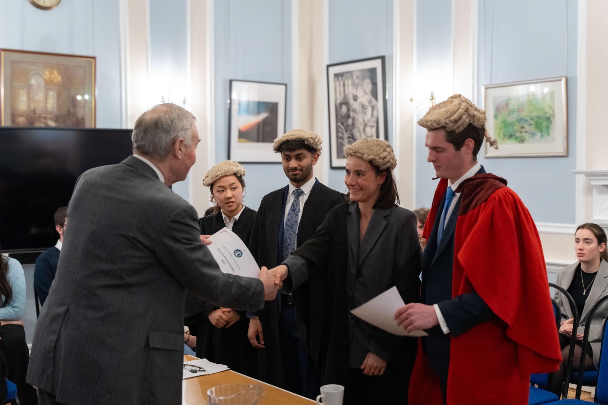 Lord Hughes shaking the hand of Celina Barton, with Duncan Roesser, Shray Modi, and Soryoung Han