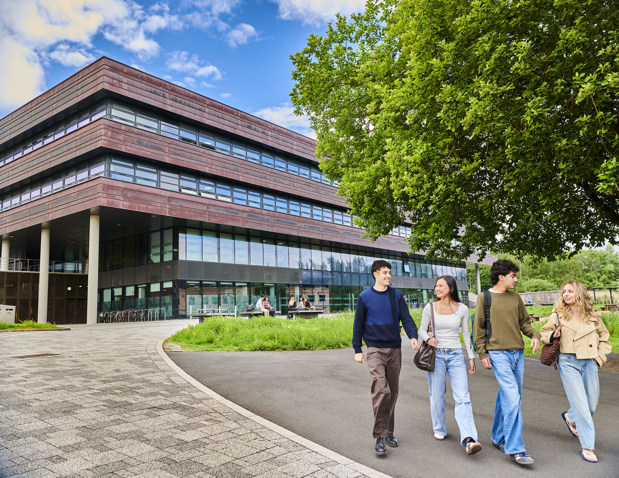 A group of four students walking in front of the Computer Science building in the summer.