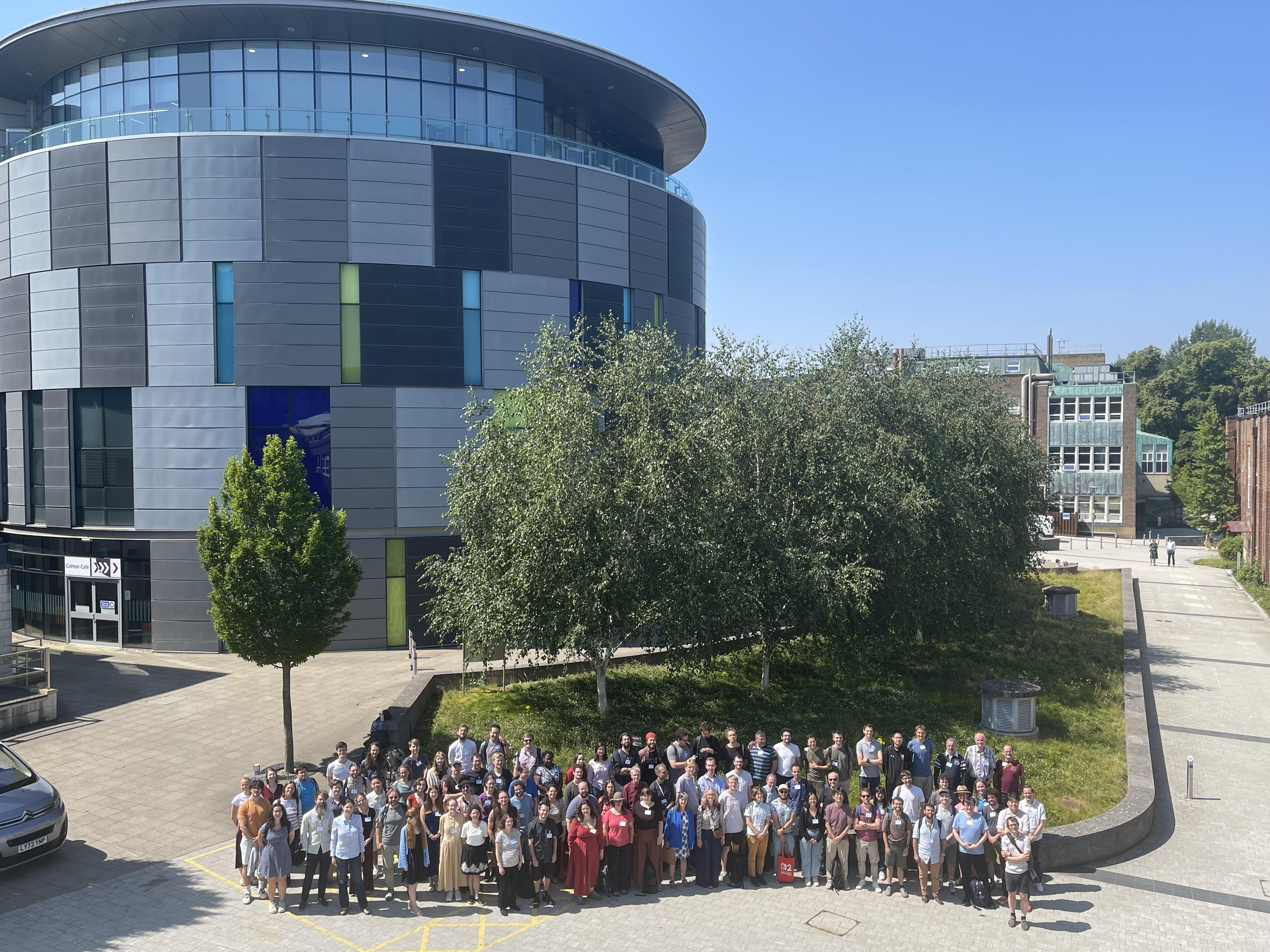 Group of participants of MEGA conference 2026 standing in front of University building, photographed from above.
