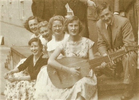 A woman with a lute in front of a group of students