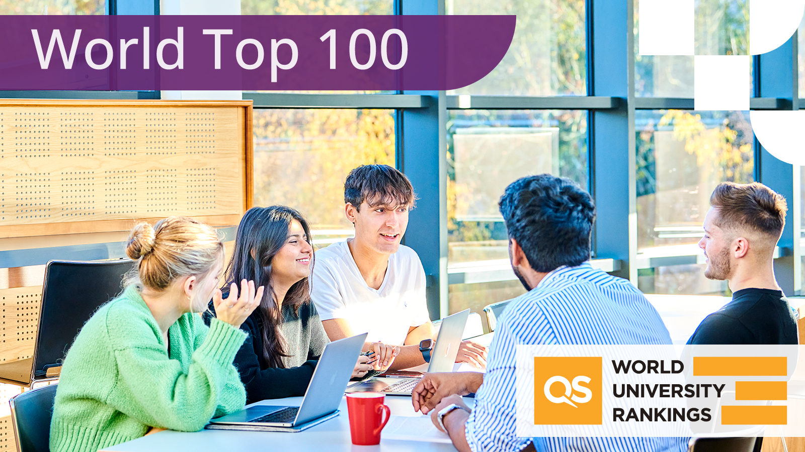 5 student sit around a table with laptops