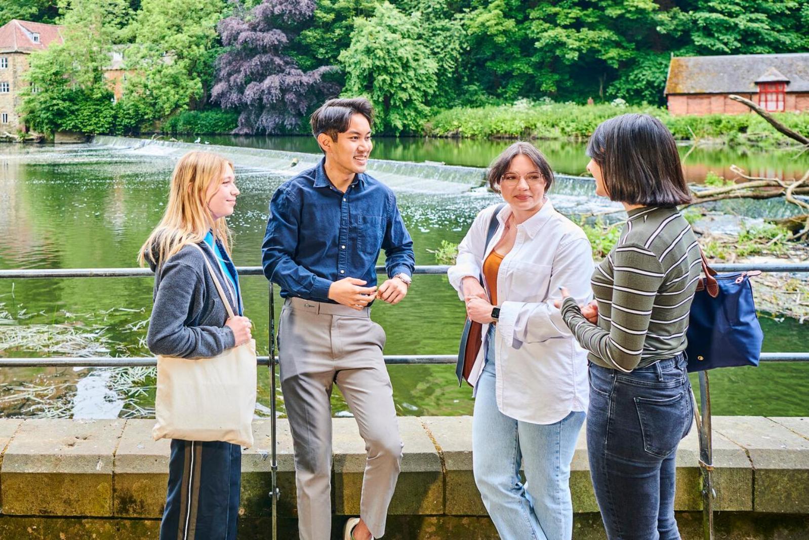 A group of students by a river in front of Durham Cathedral