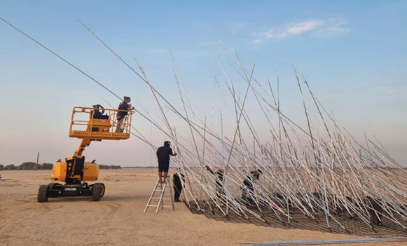 Artists setting up an artwork made up of long poles