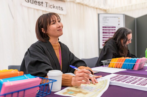 Staff member in robe helping someone at a desk