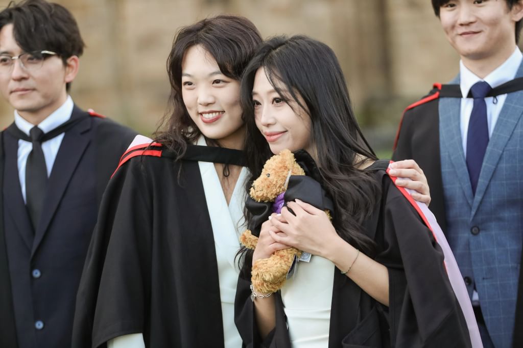 Graduates with graduate teddy bear