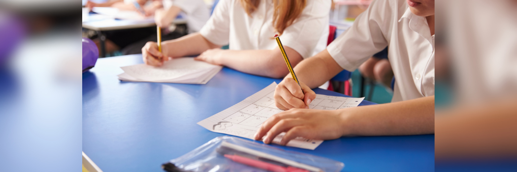 Two primary school-aged children in a class setting completing a worksheet