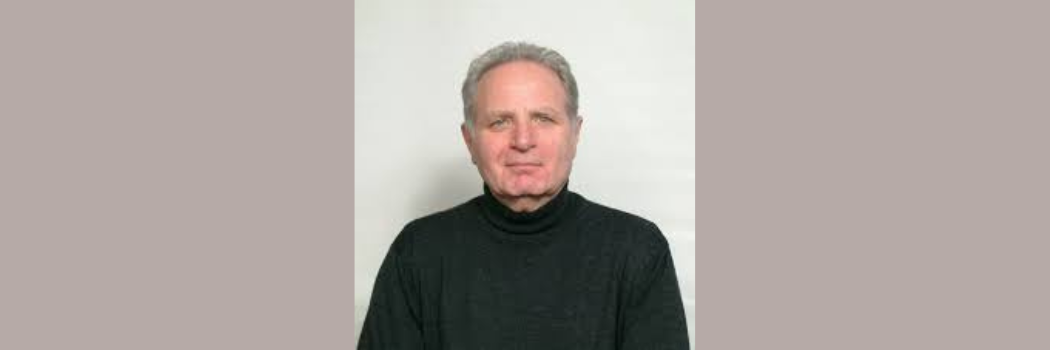 Valery is pictured in a black jumper with a plain background