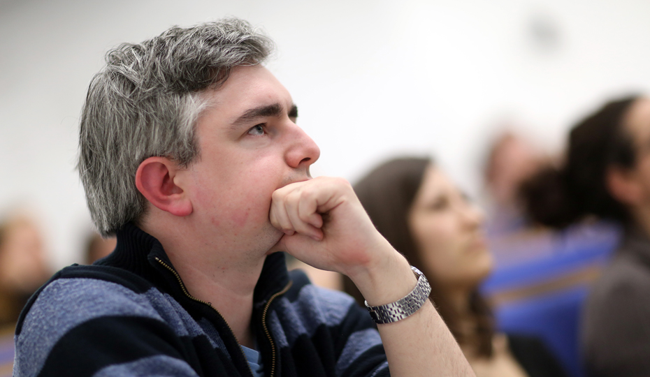 A person listening intently to a lecture in a large lecture theatre