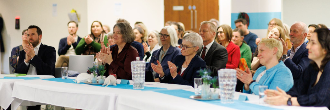 A group of people sitting at long tables clapping