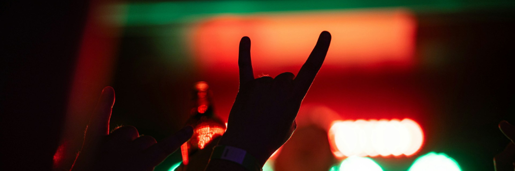 silhouette of a hand against lights at a metal music concert