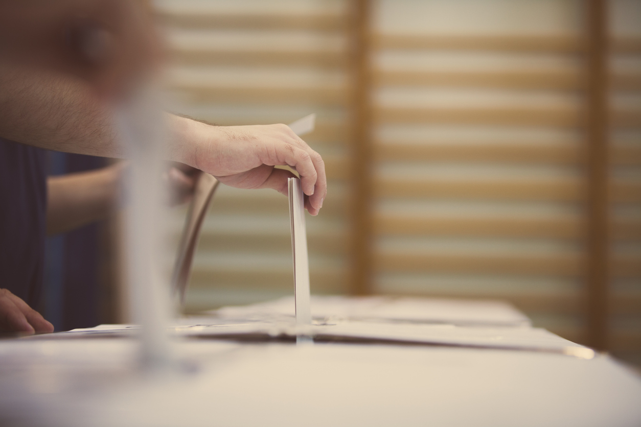 Hand of a person casting a ballot at a polling station during voting