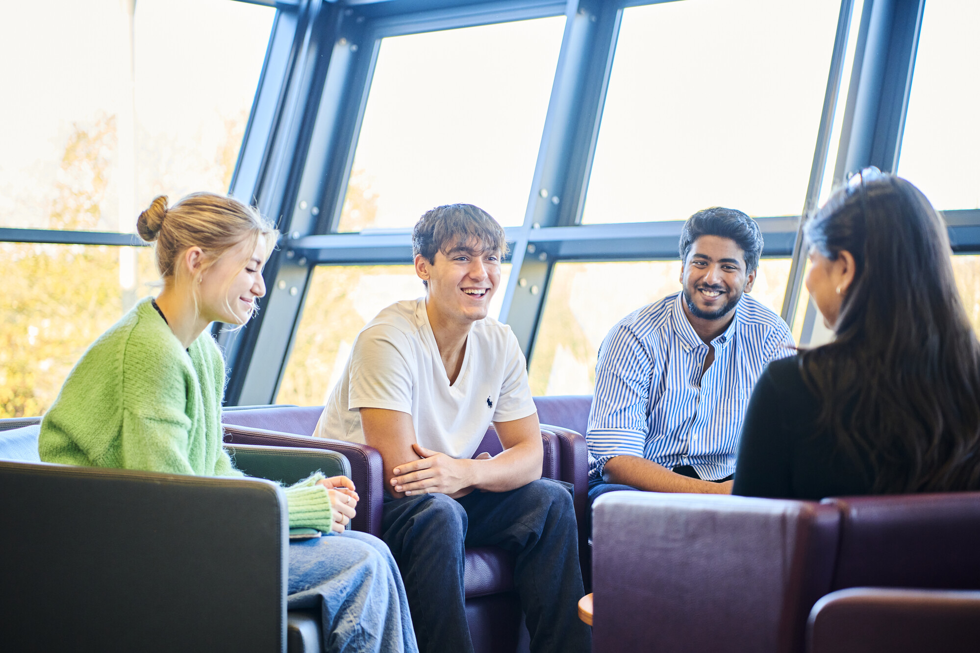 three male and one female students sat in a group talking and smiling