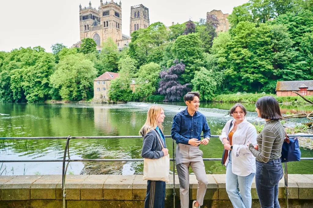 Students standing by river with Cathedral in background