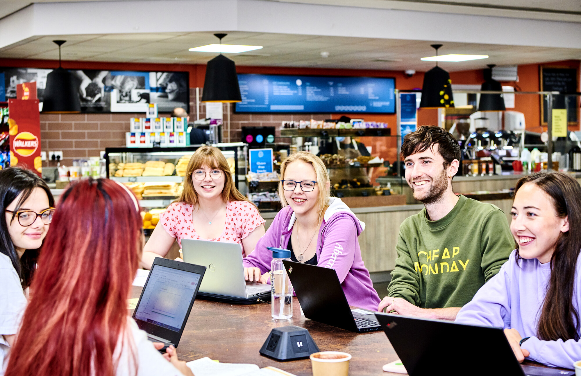Group of females and one male student sitting at a table in front of a bar