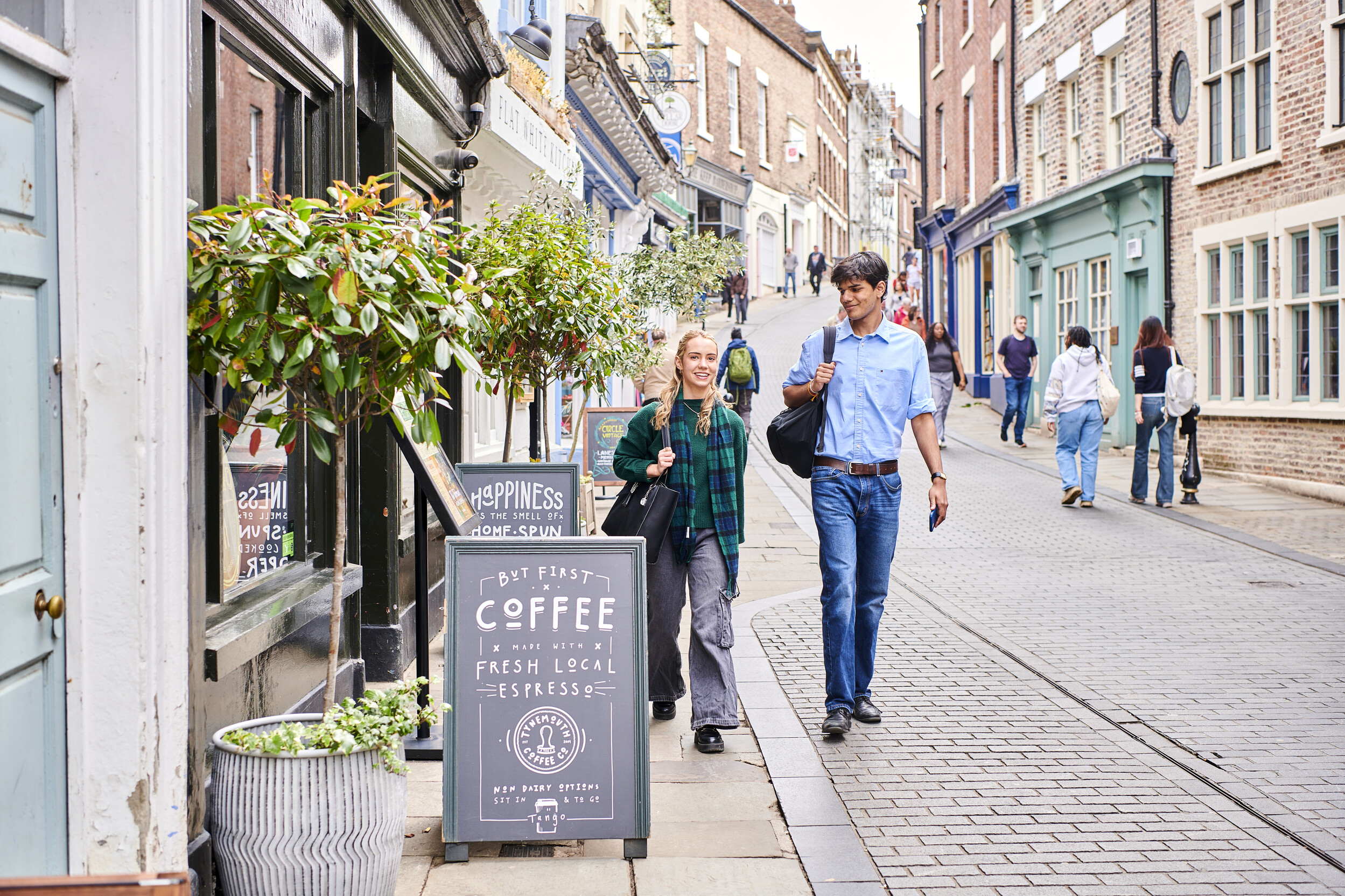 Two students walking past a coffee shop in Durham City centre
