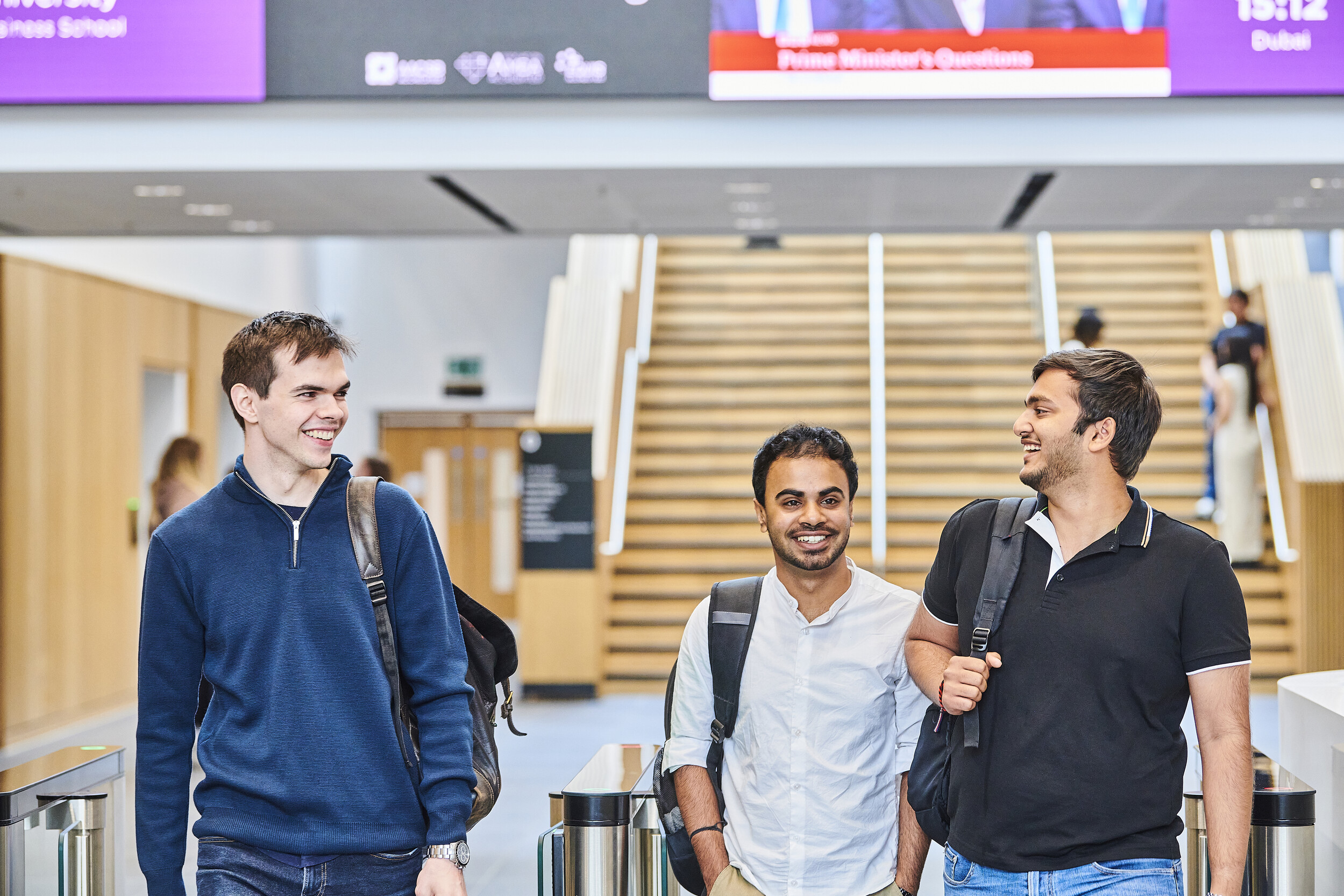 Three students walking with a flight of stairs in the background