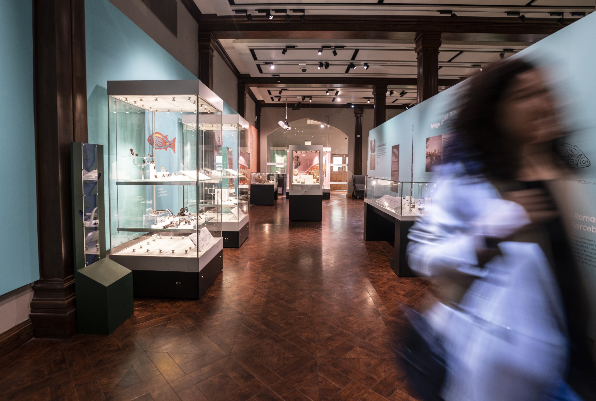 A blurry person walking through a gallery.